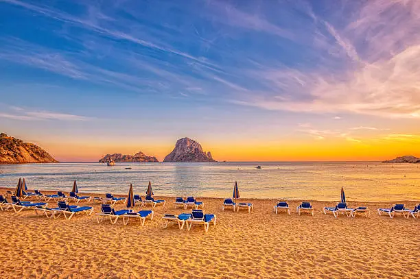 Beautiful beach, boats and Es Vedrà - a small, uninhabited rock island - in the bay of Cala D'hort, Ibiza (Spain) at sunset. 