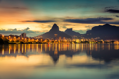 Puesta de sol detrás de las montañas en Rio de Janeiro, con reflejo de agua photo
