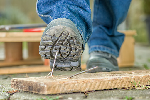 Worker with safety boots steps on a nail