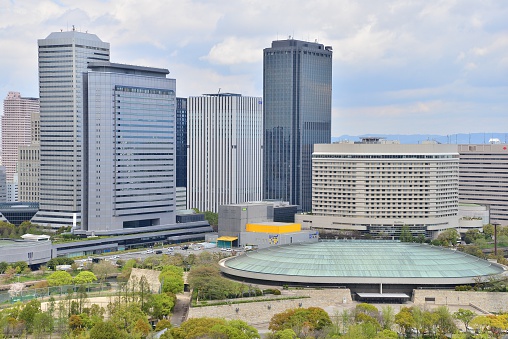 The skyline view on clear autumn day, as seen from Osaka Castle.  Office buildings tower in the background.  Osaka-jo Hall can be seen in the foreground.