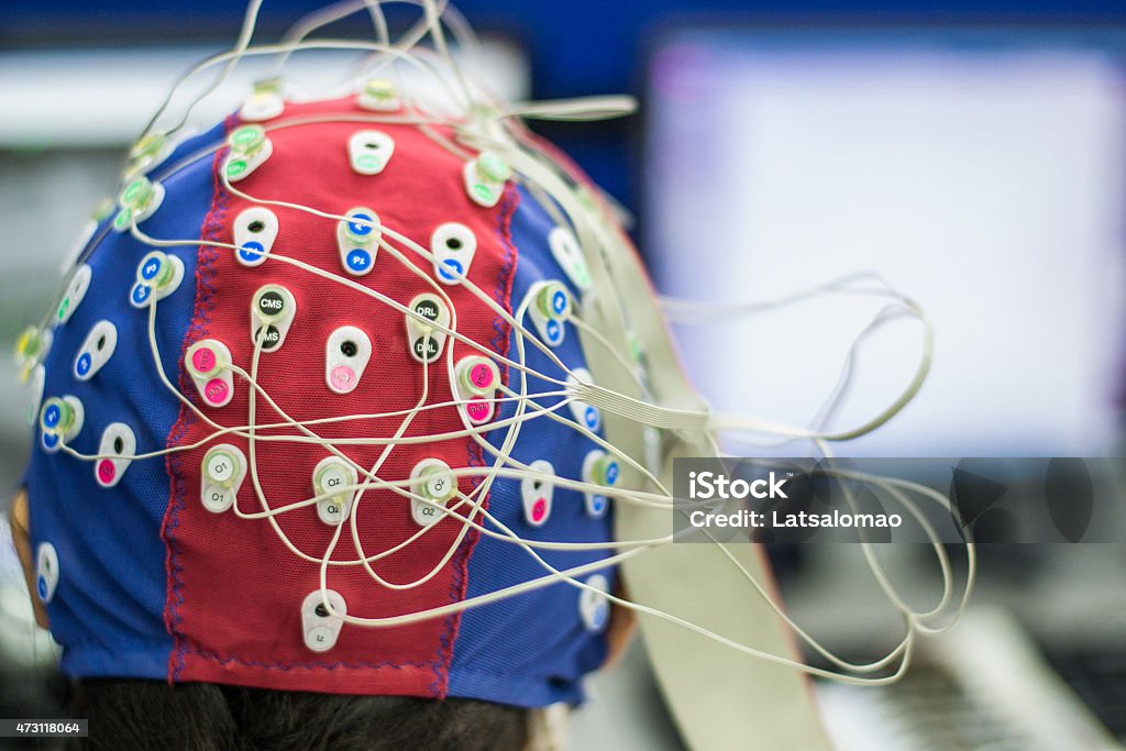 Woman with EEG and EOG electrodes in laboratory Picture of a young woman with electrodes in her head to record psychophysiological signals for research purposes. Electrocardiogram (ECG), electroencephalogram (EEG) and electrooculogram (EOG) being recorded in a laboratory environment. 2015 Stock Photo