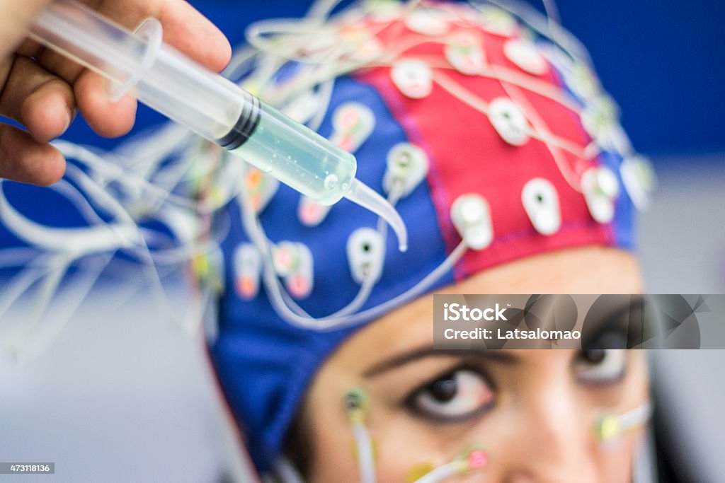 EEG conductive gel in laboratory Picture of a young woman with electrodes in her head to record psychophysiological signals for research purposes. Electrocardiogram (ECG), electroencephalogram (EEG) and electrooculogram (EOG) being recorded in a laboratory environment. Siring with conductive gel 2015 Stock Photo