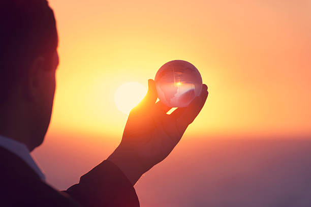 Businessman holding a world globe at dawn in silhouette over ocean. This is a success, discovery, visionary concept. It could also portray confidence, power, authority, opportunity, exploration and innovation. Back lit silhouette style