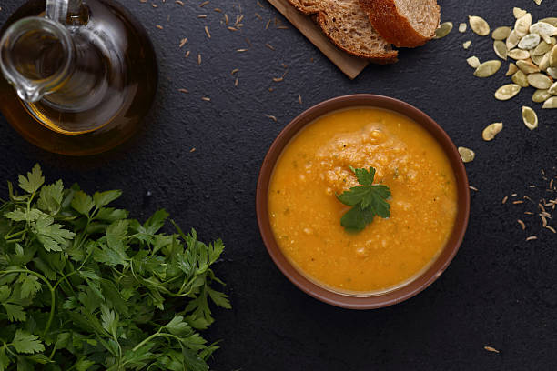 istock Pumpkin and lentil soup, bread and green on dark background 473123918