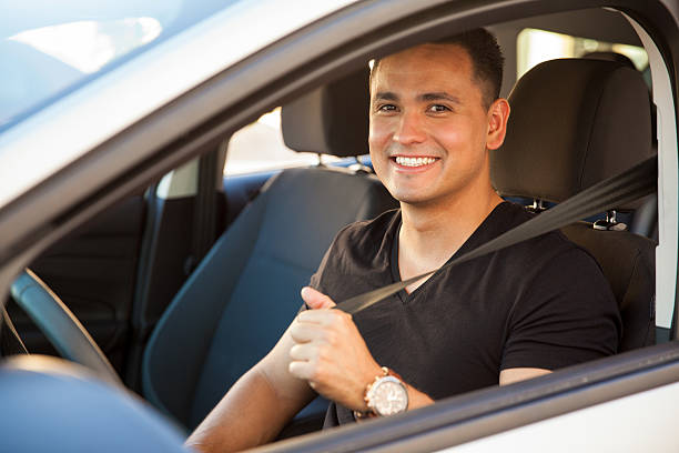 Happy guy buckling up Portrait of a happy Hispanic young man putting his seatbelt on car interior photos stock pictures, royalty-free photos & images