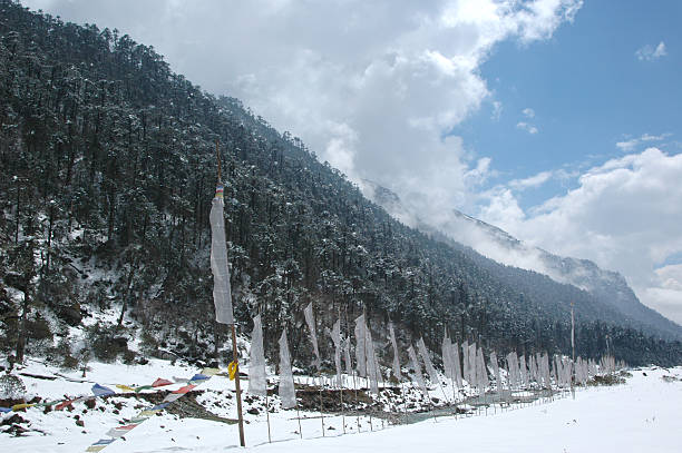 indian tricolor stone with holy buddhist flag at war memorial and snow cap mountains in background image is taken at jaswant singh war memorial bumla pass arunachal pradesh india.