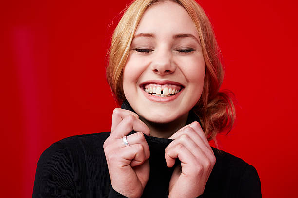 Beautiful young woman smiling Young woman laughing against red background turtleneck photos stock pictures, royalty-free photos & images