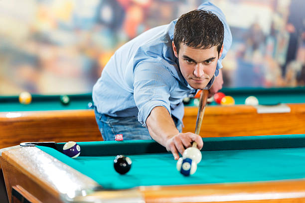 istock Young man aiming at the ball and playing billiard. 473156664