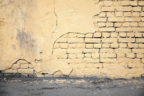 istock Yellow damaged brick wall and asphalt 473156962