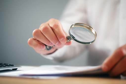 Businessman reading documents with magnifying glass concept for analyzing a finance agreement or legal contract