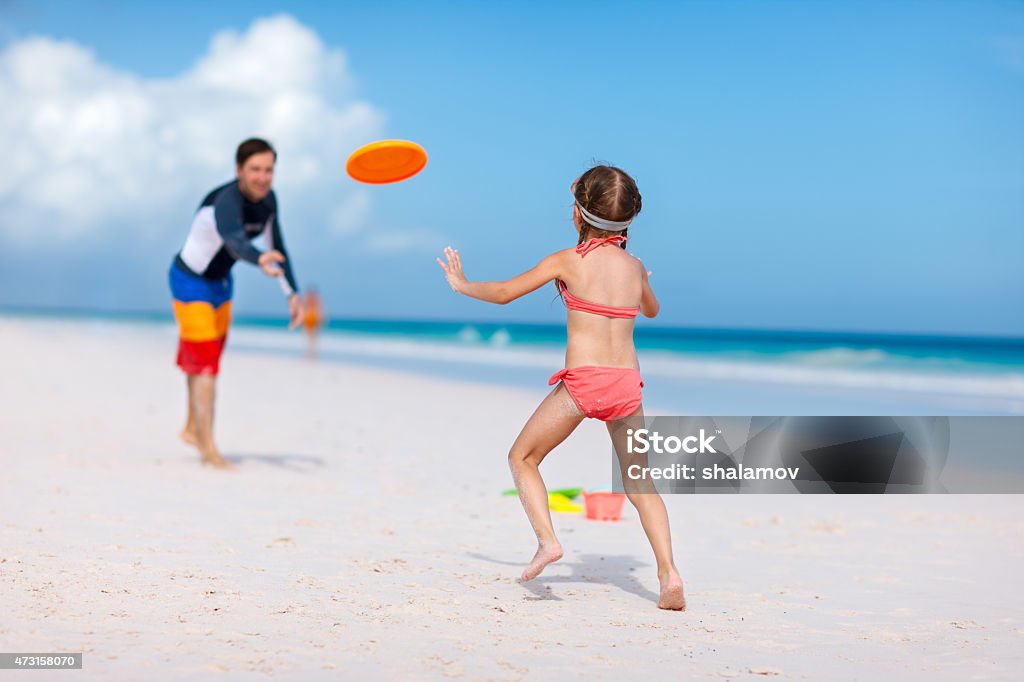 Father and daughter playing with flying disk Father and daughter playing with flying disk at beach 2015 Stock Photo