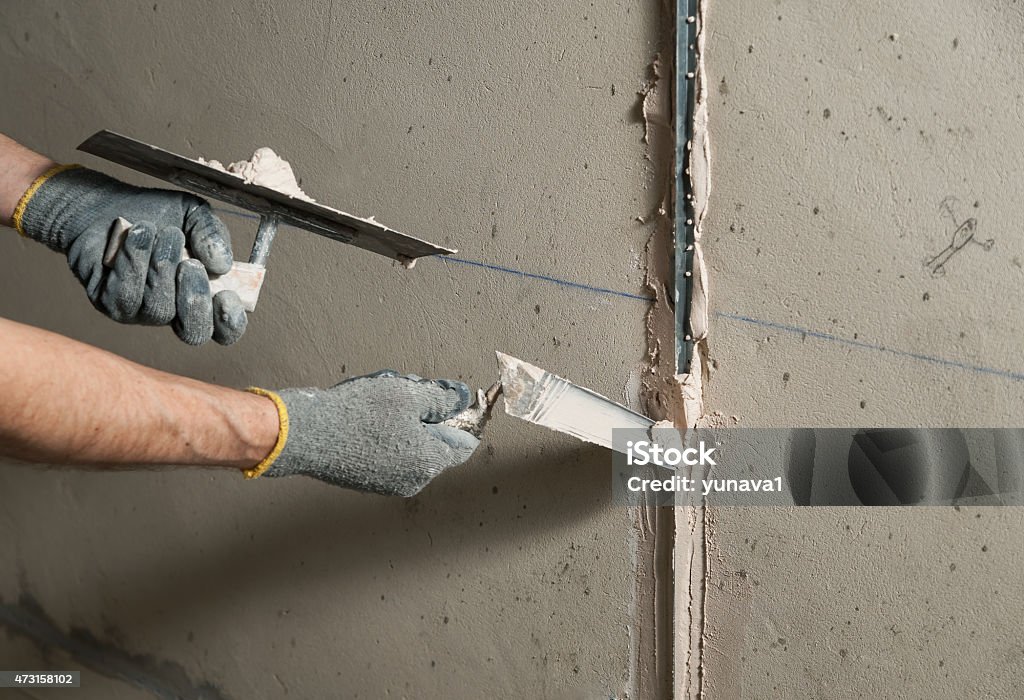 Woker fixes a guide to align the walls with stucco Man fixes a guide to align the walls with stucco in the future 2015 Stock Photo