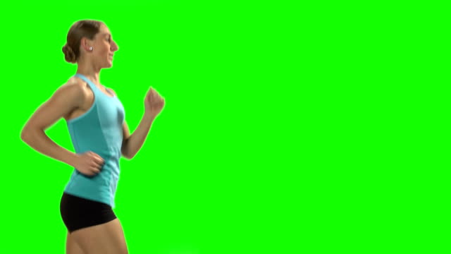 Young woman running on the treadmill. Green screen. Profile.