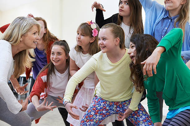 Group Of Children With Teacher Enjoying Drama Class Together Group Of Children With Teacher Enjoying Drama Class Together acting performance stock pictures, royalty-free photos & images