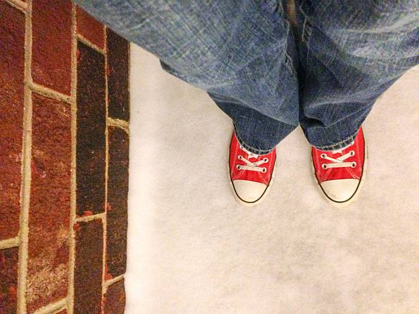 istock Red Shoes Standing in Snow Near Brick Wall 473162946