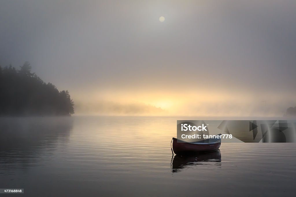Misty Morning on Lake Peaceful misty lake shot of canoe.  Lake Stock Photo