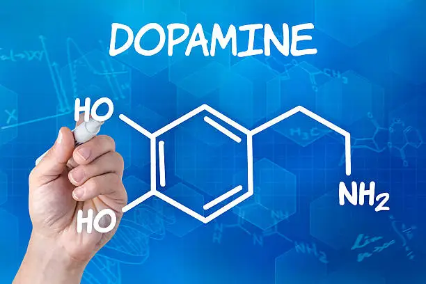 Photo of hand with pen drawing the chemical formula of Dopamine