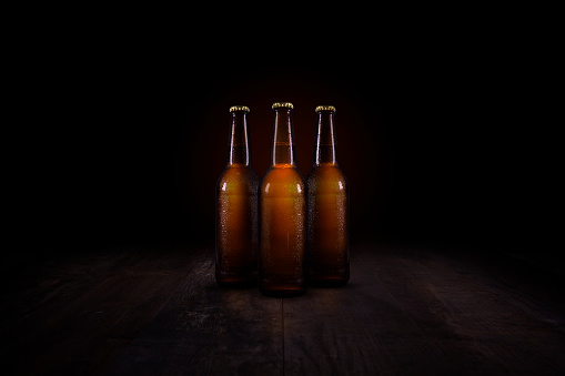 Three beer bottles on a rustic wooden table