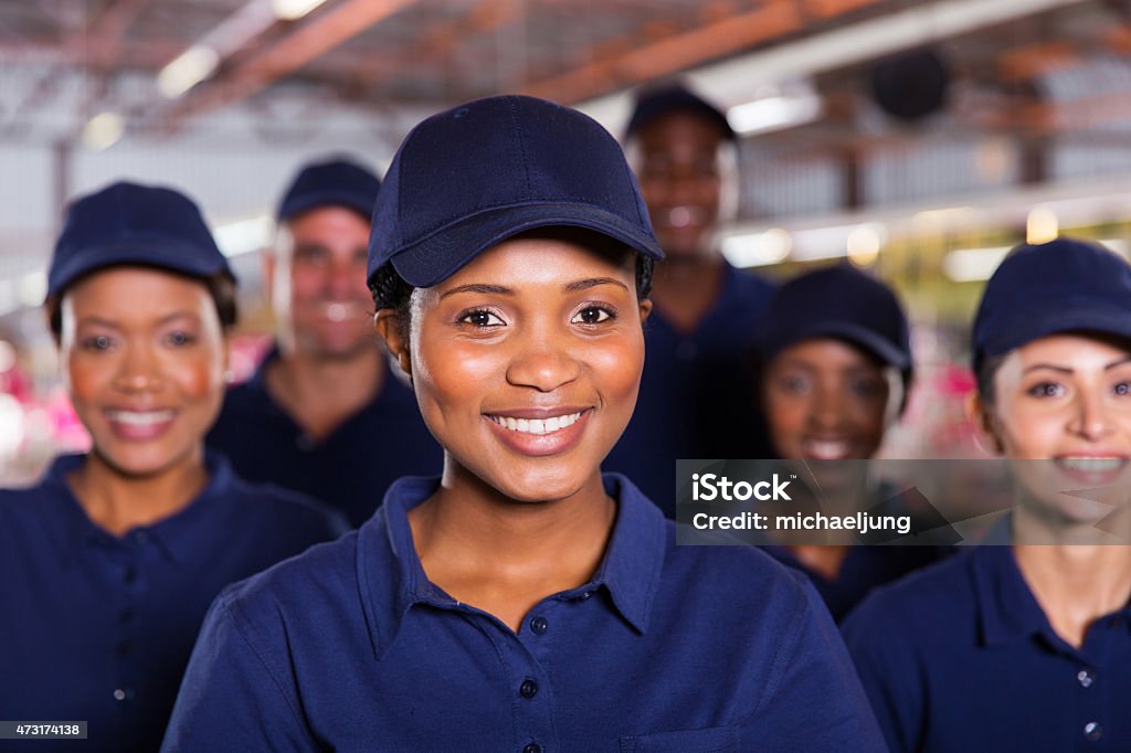 young african factory worker with colleagues happy young african factory worker with colleagues Uniform Stock Photo