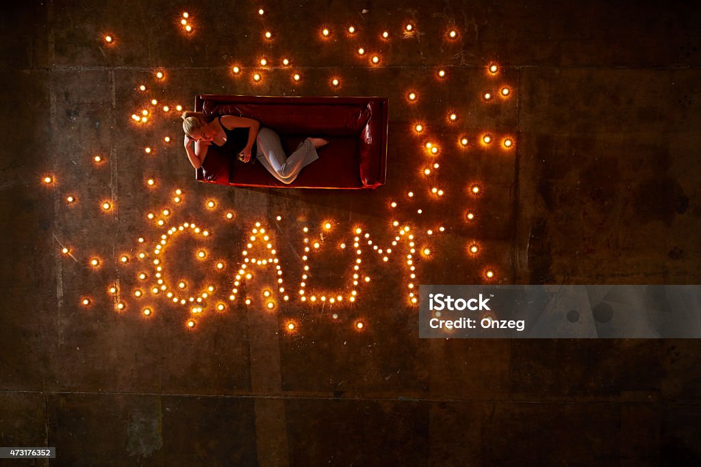 Girl resting on sofa Blonde girl resting on the sofa with candles lit, with word 'CALM' spelt out 2015 Stock Photo