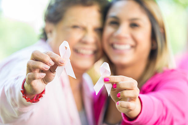 senior donna ispanica e nipote con nastri breast cancer awareness - cancer women womens issues friendship foto e immagini stock