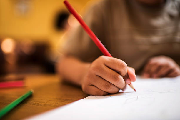 close up student man hand choose answer on exam paper sheet after read book for next test scholarship concept