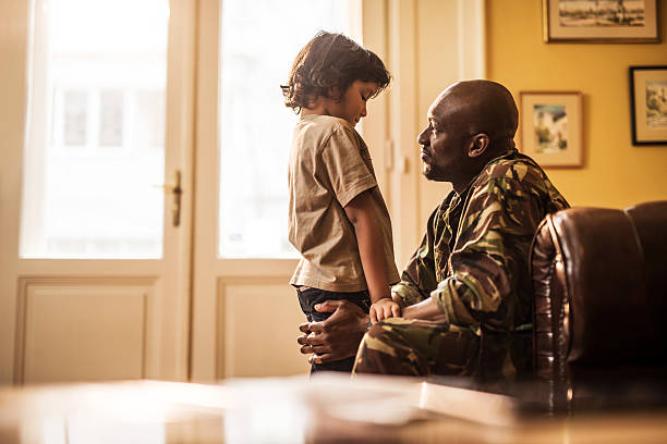 Sad African American boy talking to his military dad who is leaving to war.