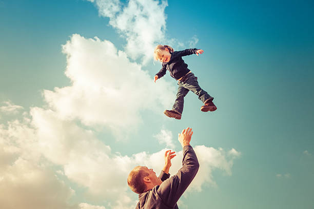 Father catching girl falling from cloudy sky