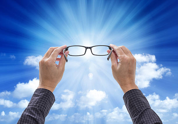 istock Hands holding eyeglasses isolated on blue sky background 473182405