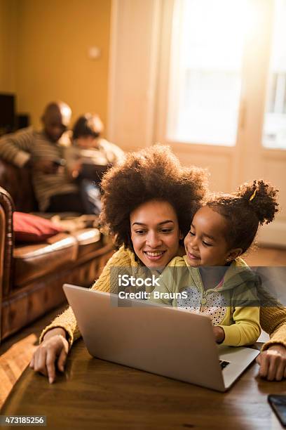 Young African American Mother And Daughter Using Laptop At Home Stock Photo - Download Image Now