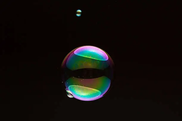 small and big colorful soap bubble against black background