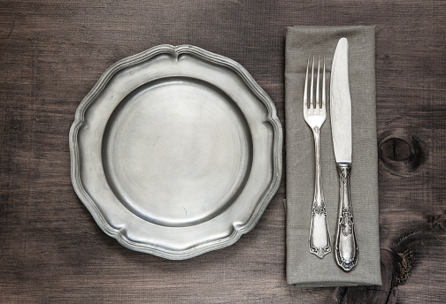 Food and Drink - Holiday Season - Place Settings.  No napkin, turquoise plate and silver fork and knife.  Wooden table.