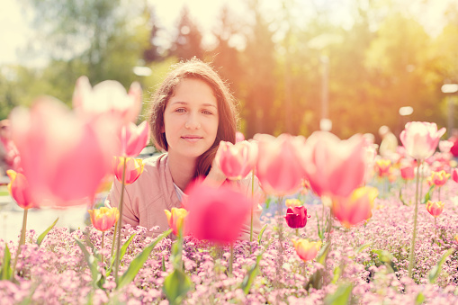 Young girl among tulips in the park