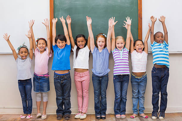 istock Cute pupils smiling at camera in classroom 473195798