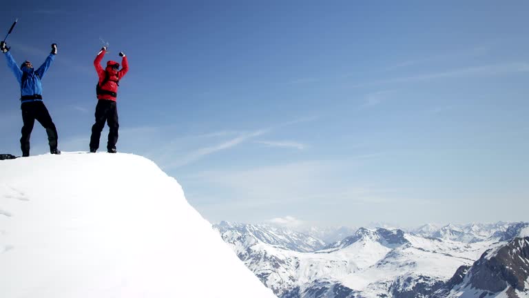 Climbers helping each other arrive at the snow-covered mountain peak