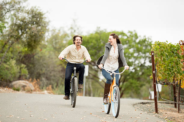 Young Couple out for a Bike Ride A heterosexual couple in love riding bicycles together outside through the vineyards in the Napa Valley while on vacation in California. napa valley stock pictures, royalty-free photos & images