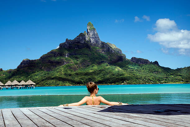 lady in the pool on Bora Bora lady in the infinity pool  on the beach of a luxury vacation resort in the lagoon and looking on the Otemanu mountain on the tropical island of Bora Bora, near Tahiti, French Polynesia, Pacific ocean french polynesia stock pictures, royalty-free photos & images