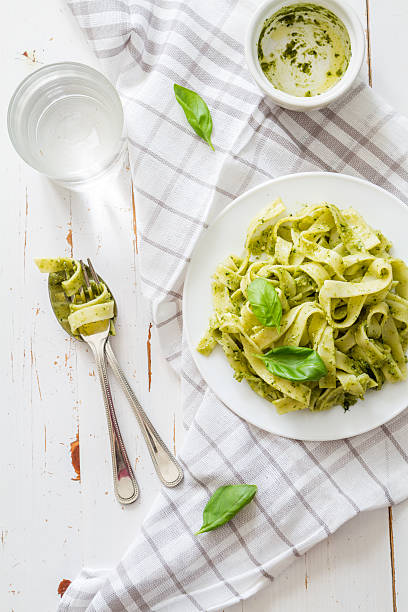 istock Pesto pasta on white plate, basil leafs, water 473210030