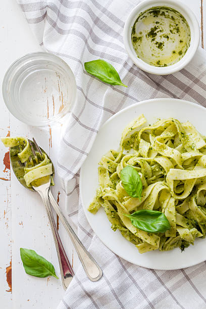 istock Pesto pasta on white plate, basil leafs, water 473210032