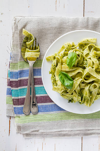 istock Pesto pasta on white plate, basil leafs, white wood background 473210044