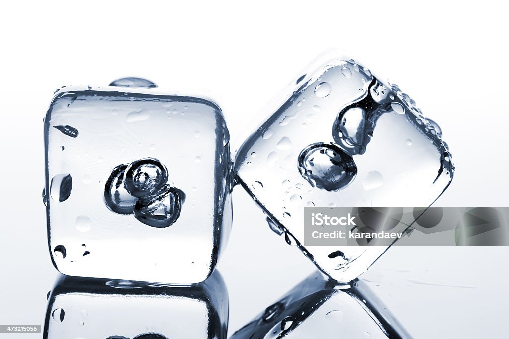 Two melting ice cubes with water dew Two melting ice cubes with water dew on white background 2015 Stock Photo