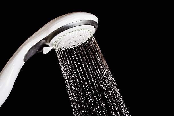 istock Modern shower head  with running water  isolated on black backgr 473215290