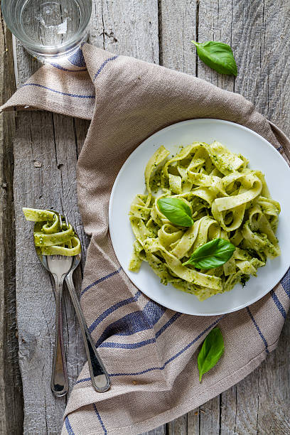 istock Pesto pasta on white plate, basil leafs, water 473217218