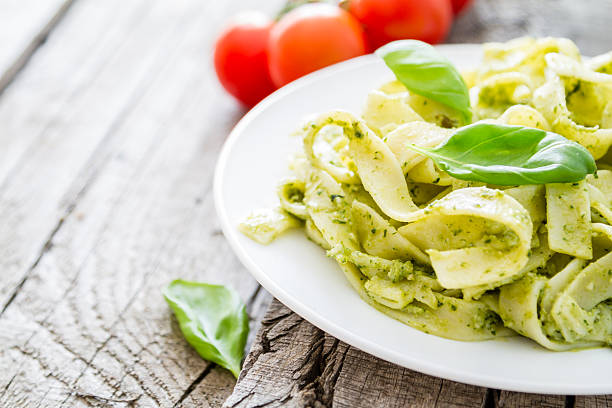 istock Pesto pasta on white plate, basil leafs, cherry tomatoes 473217224