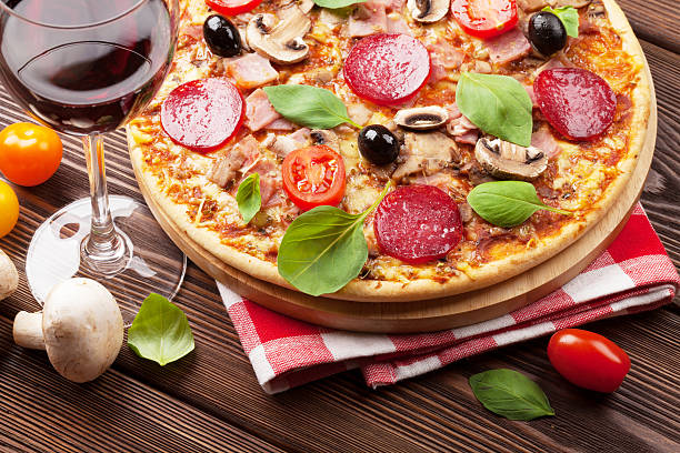 istock Italian pizza with pepperoni, tomatoes, olives, basil and red wi 473217882