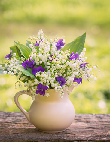 Beautiful bouquet of lilies of the valley and violets on the table