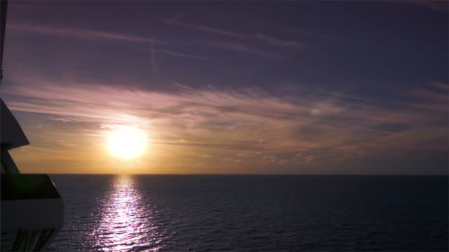 Golden sunset on dark ocean from external side of ship