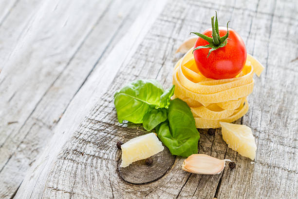 istock Raw pasta, cherry tomato, basil leaf ,wood background, closeup 473233484