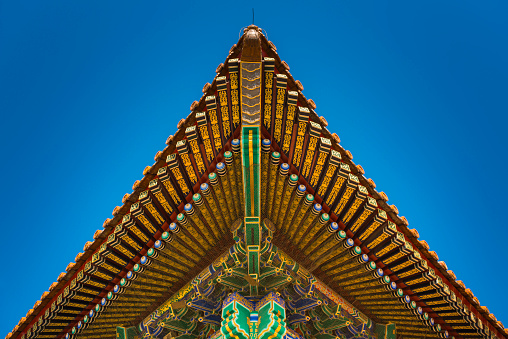 The ornate wooden eaves and their brightly coloured painted decorations of a temple pagoda in the Forbidden City, the iconic UNESCO World Heritage Site in the heart of Beijing, China's vibrant capital city. ProPhoto RGB profile for maximum color fidelity and gamut.