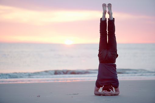 Male guy doing headstand at the beach of St.Peter-Ording, Germany